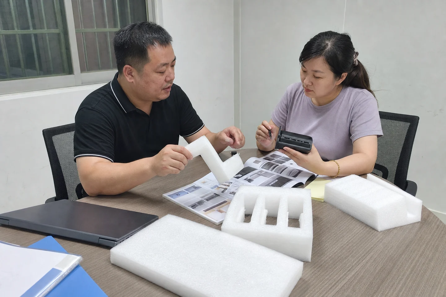 制造企业老板与销售主管在会议桌前查看EPE包装资料和询盘记录